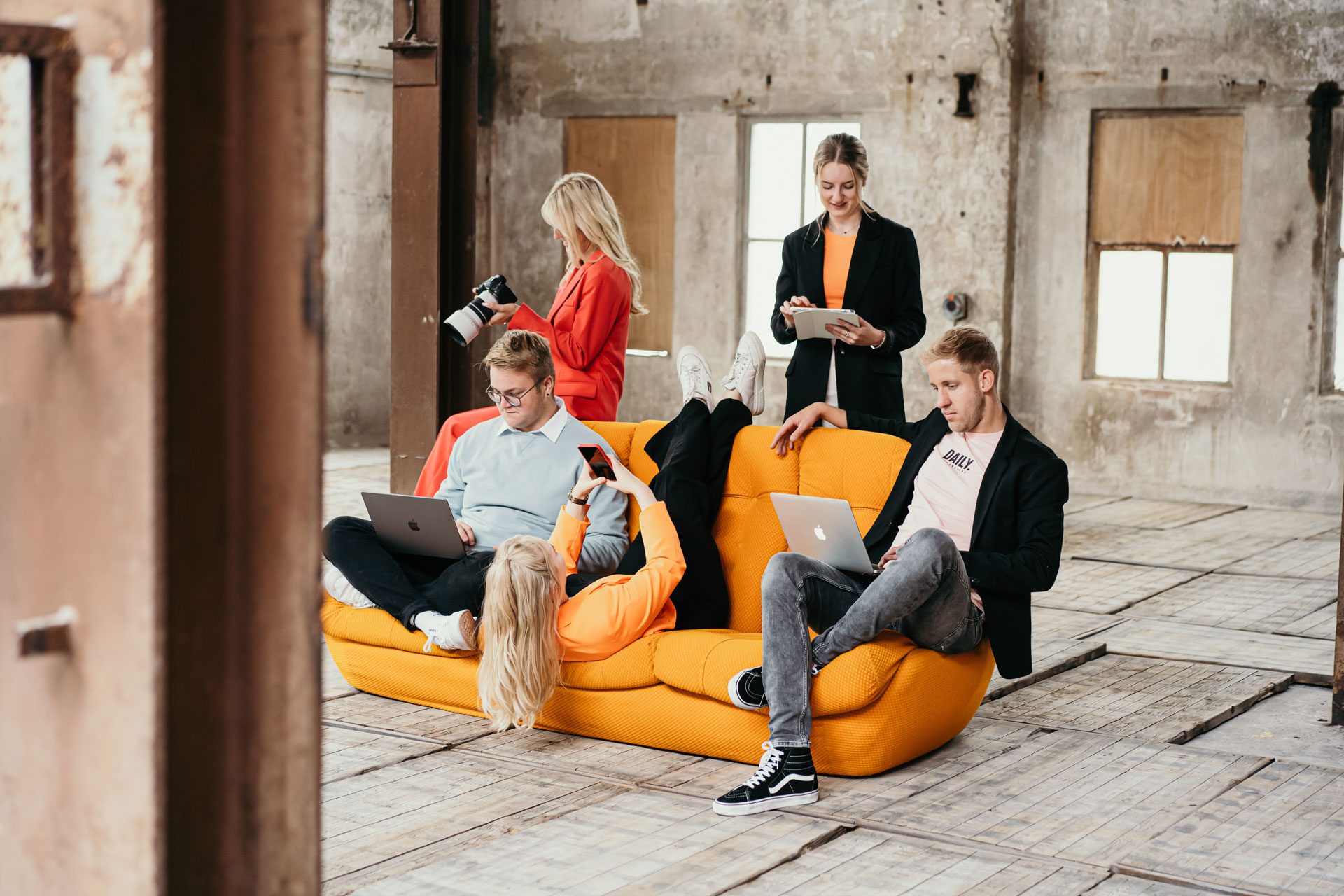 Team Modern Visuals op een bank met allemaal een device in hun handen